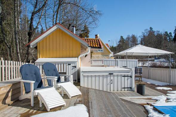 Stort trädäck mellan huset, poolen och bastun