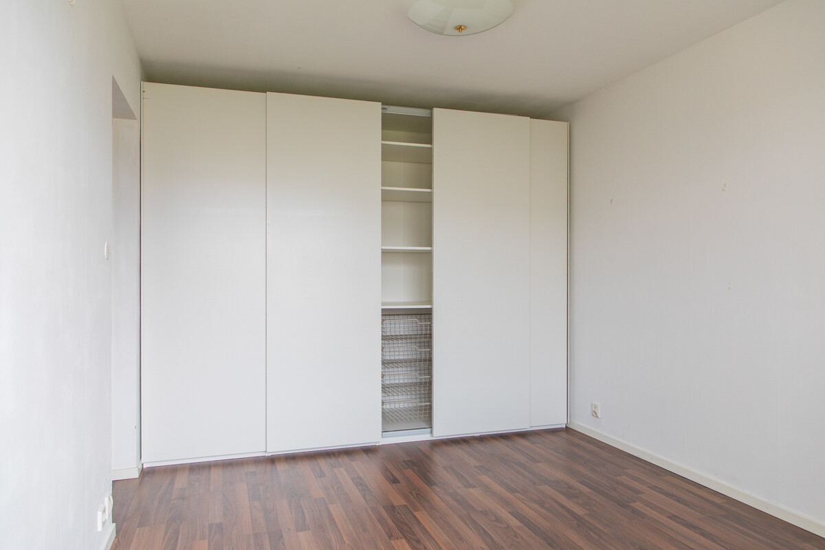 Sovrum med väl inredd skjutdörrsgarderob